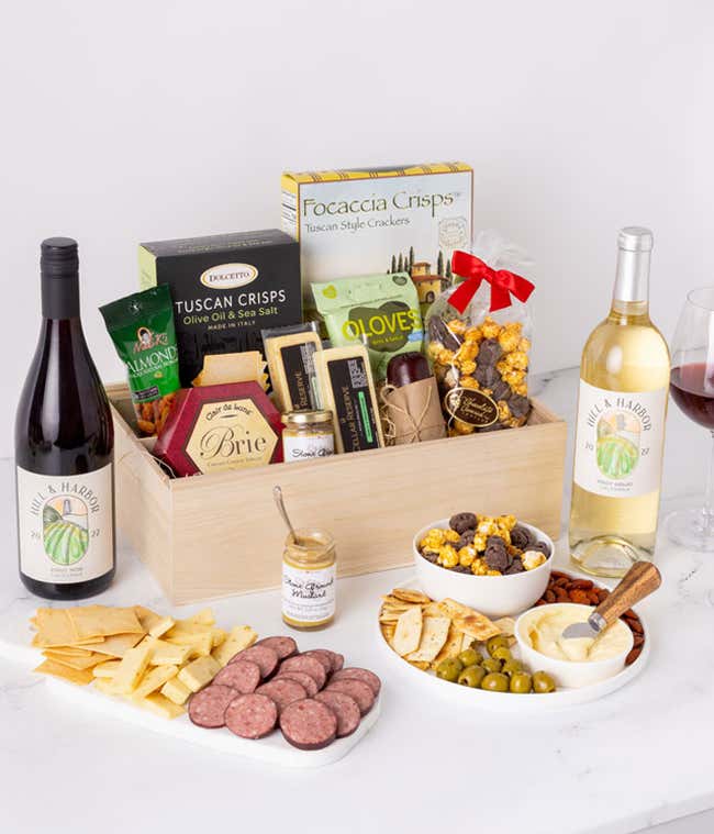 Festive gift box filled with holiday treats, including peppermint bark and chocolate-covered pretzels decorated with red, green, and white sprinkles. The box is tied with a red ribbon and bow, creating a cheerful holiday presentation.